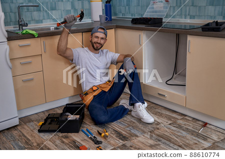 Happy young caucasian worker with raised hand holding hammer Happy young caucasian worker with raised hand holding hammer 88610774
