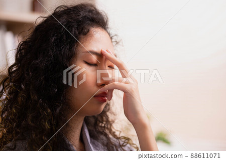 To guide her breath, an Asian lady touches her forehead with her fingers. To get started with yoga and meditation 88611071