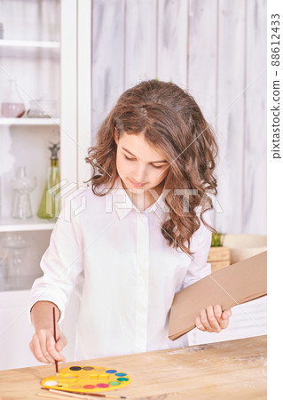 Young girl at paint studio portrait. Curly pretty child. Student looking tablet 88612433