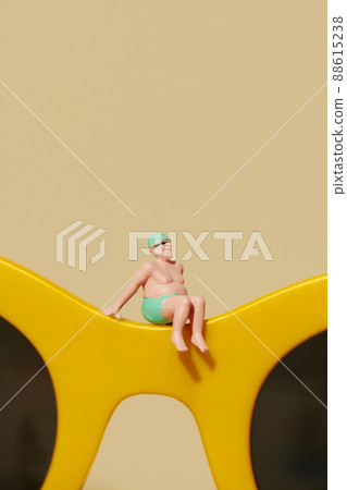 miniature man sitting on a pair of sunglasses 88615238
