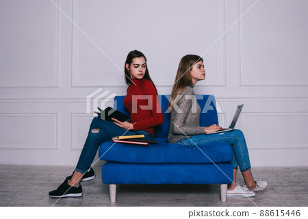 Pensive women with laptop and books sitting on sofa 88615446