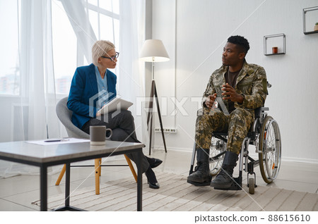 Paraplegic soldier in wheelchair talking with therapist 88615610