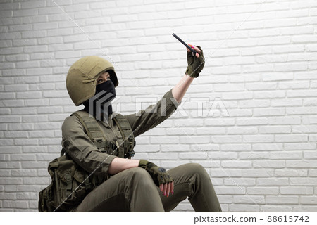 a soldier girl in a helmet takes a selfie on a mobile phone 88615742