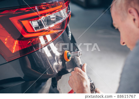 Car detailing, concept of details and polishing cars. hands of a professional car service male worker with orbital polisher polishing a white luxury car hood in a car repair shop 88615767