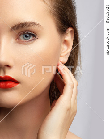 Close up beauty of a half face of a woman with wet radiant skin and big gray eyes. Fashionable natural makeup and wet facial hair. Pink lipstick with kissed lips 88615929