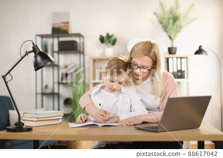 Mother helping his son with his homework at home. Mother helping his son with his homework at home. 88617042