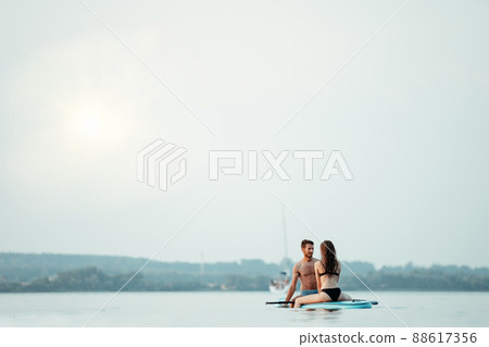 young couple in love is kissing sitting on the SAP board . young couple in love is kissing sitting on the SAP board . 88617356
