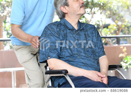 Wheelchair-riding elderly and male caregivers Wheelchair-riding elderly and male caregivers 88619086