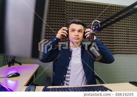serious radio host broadcasts live reads news on computer screen. 88619205