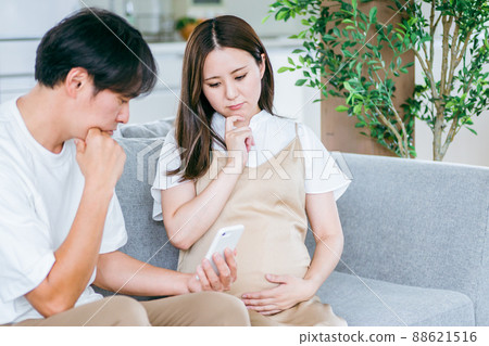 Pregnant women and men looking at smartphones (worried) 88621516