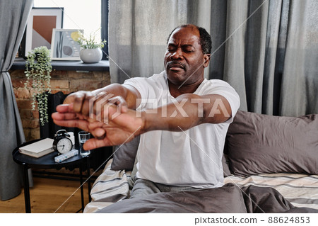 Active senior man doing sit ups right after sleep while sitting in bed Active senior man doing sit ups right after sleep while sitting in bed 88624853