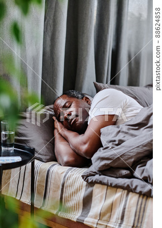 Tired mature African American man sleeping peacefully in bed in the morning 88624858