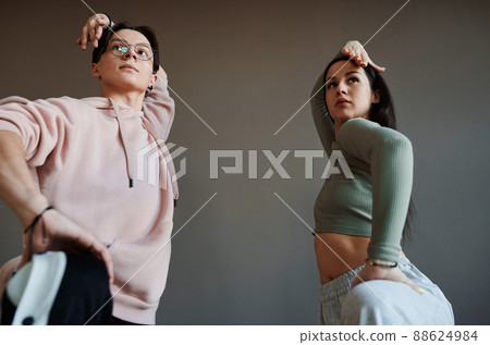 Two active teenagers keeping their arms over heads while training in studio 88624984