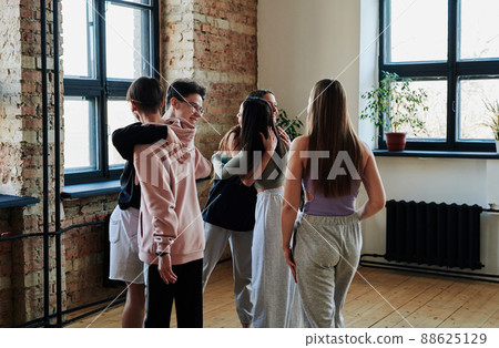Group of happy teenagers giving hugs to one another before repetition in studio 88625129