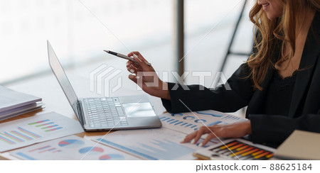 Asian Business woman working to analyze technical price graph and indicator with business team talking by cell phone. account or saving money or insurance concept. 88625184