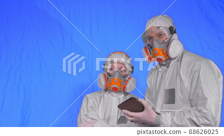 Scientist virologist in respirator makes write in an tablet computer with stylus. Man and woman wearing protective medical mask. Chroma key blue. 88626025