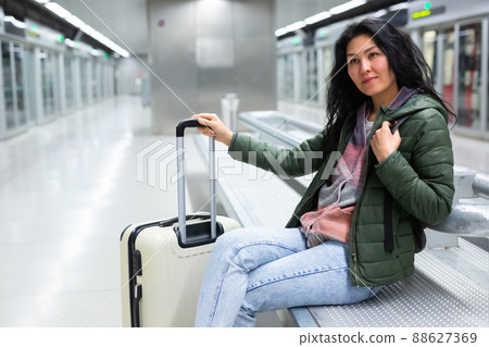 Woman sitting in subway station and waiting for train arrival 88627369