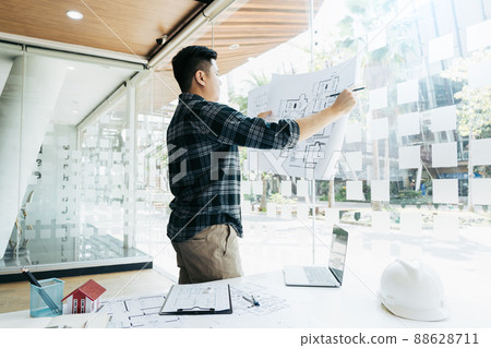 Interior designer or architect reviewing blueprints and holding pencil drawing on desk at home office. 88628711