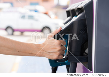 Unrecognizable Asian woman holding aa DC - CCS type 2 EV charging connector at EV charging station, woman preparing an EV - electric vehicle charging connector for recharge a vehicle. Unrecognizable Asian woman holding aa DC - CCS type 2 EV charging connector at EV charging station, woman preparing an EV - electric vehicle charging connector for recharge a vehicle. 88628977