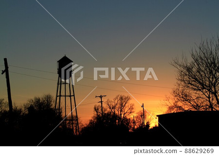 A water tower and tree silhouettes at Sunset with a colorful sky A water tower and tree silhouettes at Sunset with a colorful sky 88629269