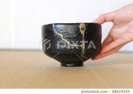 用金繕（金繕）修復過的黑色抹茶茶碗，雙手捧著用來迎接客人：茶道和日本傳統工藝。 88629583