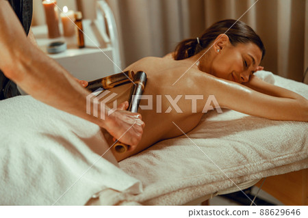 Male therapist doing back and shoulder massage for woman using hollow bamboo canes 88629646