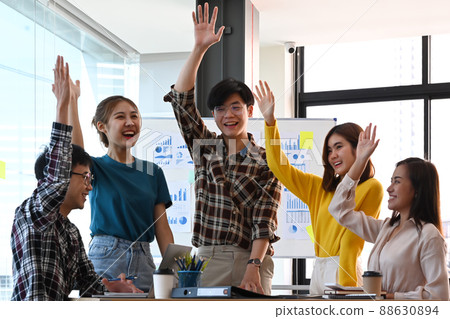 Excited business team celebrating corporate victory together in office. 88630894