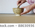 A woman in a kimono makes tea in a Kintsugi matcha bowl 88630936