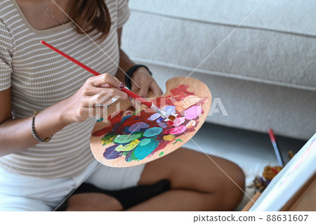 Cropped shot creative woman holding painting brush and mixing color oil painting on palette. 88631607