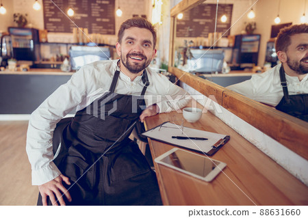 Cheerful bearded man working in coffee shop Cheerful bearded man working in coffee shop 88631660
