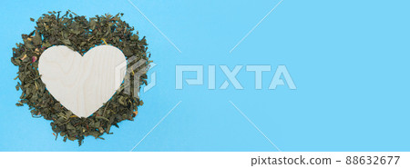 Banner with loose leaf green tea and an empty wooden heart. Blue background. Dried green tea leaves. Flat lay. Top view. Copy space. place for text. Layout for design. Banner with loose leaf green tea and an empty wooden heart. Blue background. Dried green tea leaves. Flat lay. Top view. Copy space. place for text. Layout for design. 88632677
