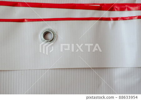 Red and white advertising banner with metal eyelets. Wide-format printing products. Folded banner in close-up 88633954