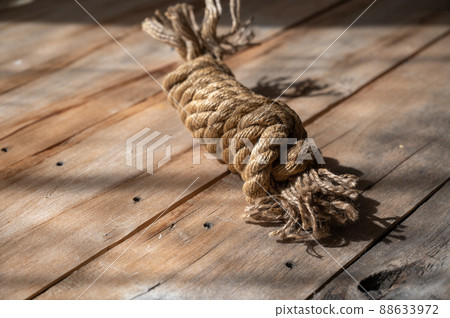 Coiling a natural rope against a wooden background. Rough, cracked boards. Natural lighting. Coiling a natural rope against a wooden background. Rough, cracked boards. Natural lighting. 88633972