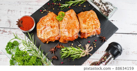 Three pieces of chicken thighs marinated in red sauce on a kitchen cutting board, on a light background, banner. Convenience food, quick cook, semi-cooked food.Top view. 88634159