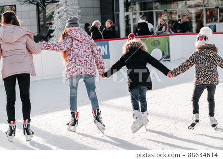 Soft,Selective focus.Group of teenage friends ice skating on an ice rink.Enjoying winter outdoor activities.Outdoor.Winter sport.Learning how to skating on ice. Soft,Selective focus.Group of teenage friends ice skating on an ice rink.Enjoying winter outdoor activities.Outdoor.Winter sport.Learning how to skating on ice. 88634614