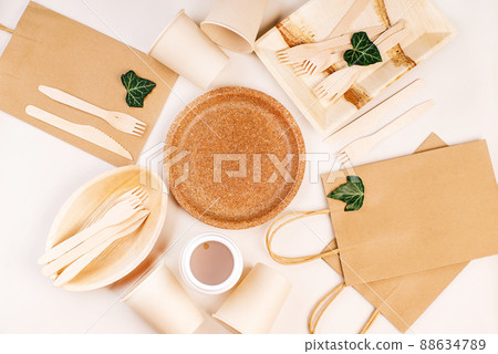Eco craft paper tableware,cups,fast food containers.Recycling,eco-friendly concept.Disposable eco cutlery,plates,spoons,knives,forks on a light background.Craft paper bag for food delivery.Copy space. 88634789