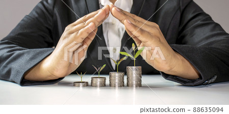 trees growing on a pile of coins in the hand of a middle-aged man. Retirement Financial Planning Ideas saving money and cash and investment to create financial stability after retirement 88635094