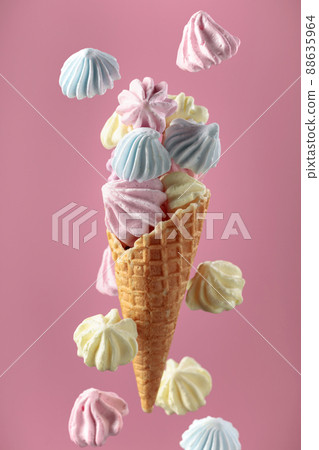 Meringue in a waffle cone on a pink background. Meringue in a waffle cone on a pink background. 88635964
