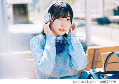 High school girl listening to music on the platform of the station High school girl listening to music on the platform of the station 88637176