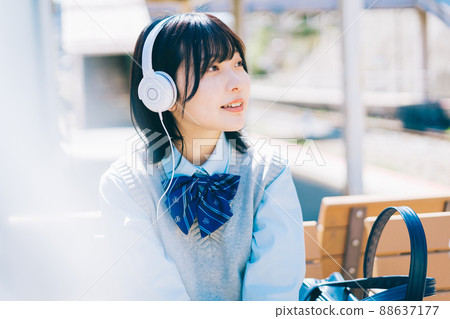 High school girl listening to music on the platform of the station 88637177