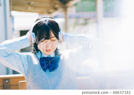 High school girl listening to music on the platform of the station 88637181