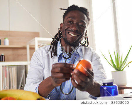 Afroamerican nutritionist looking at camera and showing healthy fruits in the consultation. 88638060
