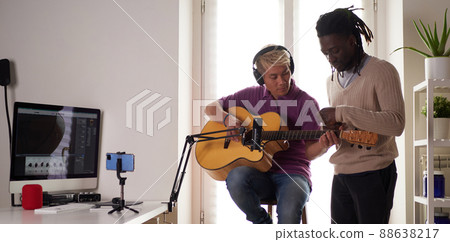 A personal afroamerican tutor explains to his asian student how to play studied chord correctly. Musical education at home 88638217