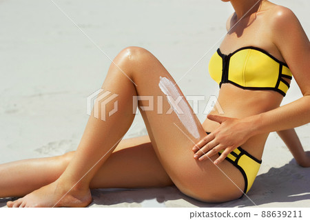 Closeup on female hand applying sun screen creme on leg 88639211
