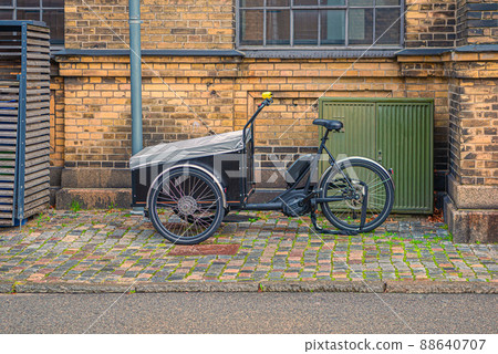 A tricycle cargo family bike with box for the transport of children stands on a street in old town. Copenhagen, Denmark 88640707