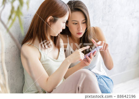 兩個女人和朋友一起看智能手機 兩個女人和朋友一起看智能手機 88642196