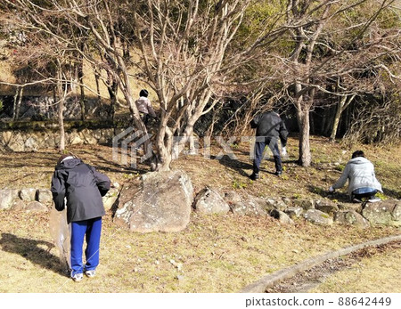 Four people are picking up trash at neighborhood association events, park cleaning, and winter parks with trees with plastic bags for trash. Four people are picking up trash at neighborhood association events, park cleaning, and winter parks with trees with plastic bags for trash. 88642449
