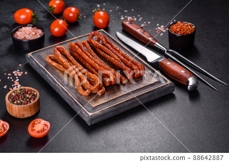 Smoked hunting sausages on a black stone background. Top view. Free copy space Smoked hunting sausages on a black stone background. Top view. Free copy space 88642887