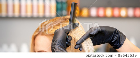 Beautiful young blonde woman with long straight blonde hair getting a haircut at the hairdresser salon 88643639