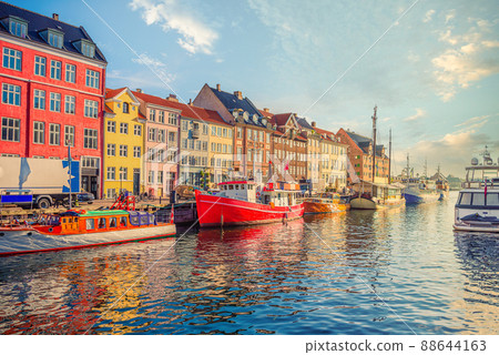 An old red and white fishing boat stands among other ships and yachts near the old small multi-colored houses in the Nyhavn canal. Copenhagen, Denmark 88644163